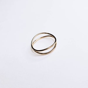 May include: A gold-toned ring with two overlapping bands.