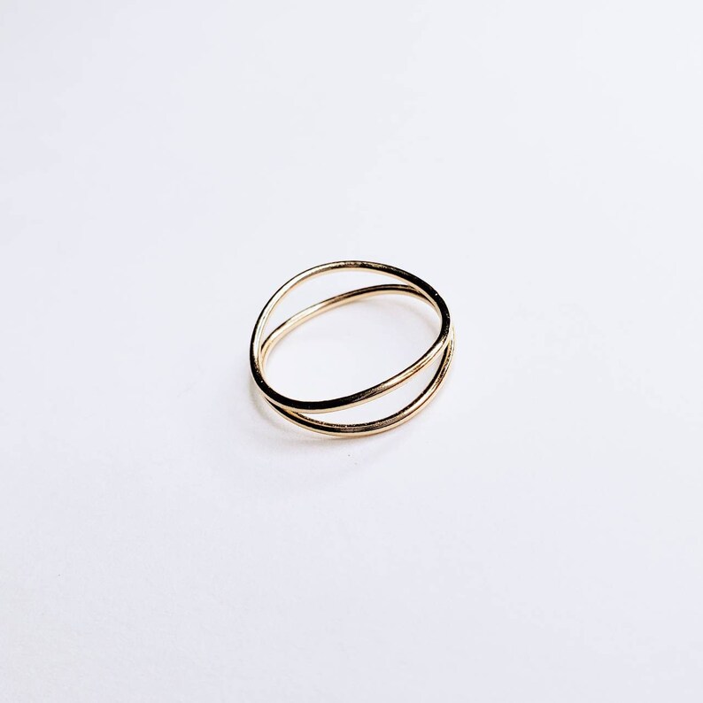 May include: A gold-toned ring with two overlapping bands.