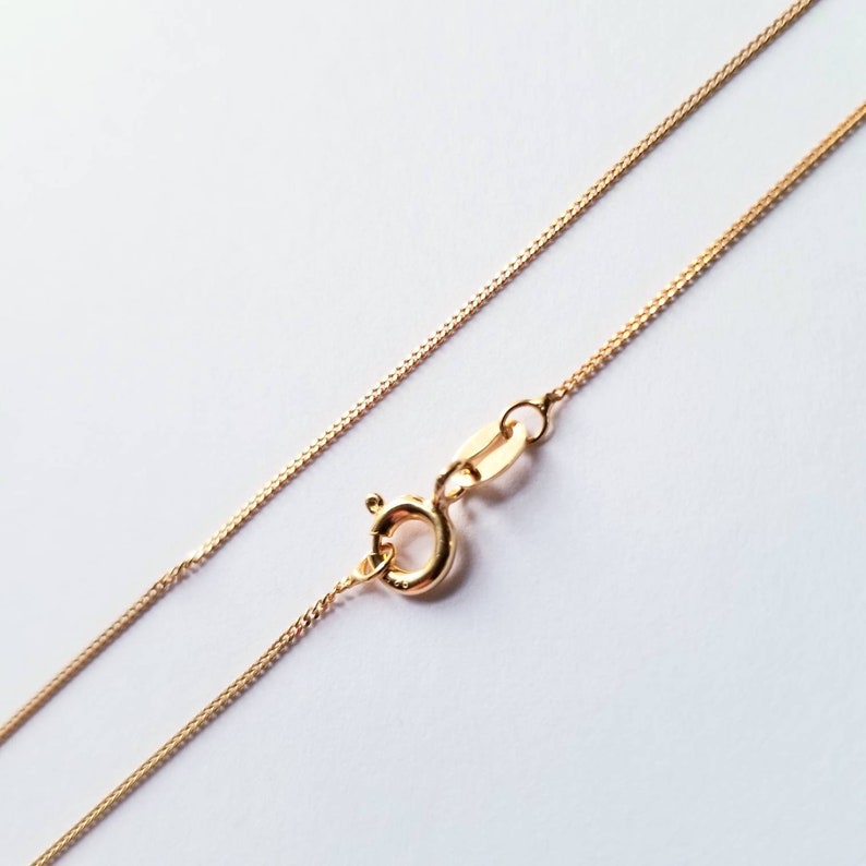 May include: A gold chain necklace with a lobster clasp closure.