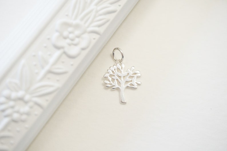 Pu&ograve; includere: Un ciondolo in argento a forma di albero della vita. Il ciondolo &egrave; un design delicato a taglio con un tronco d'albero e rami dettagliati.