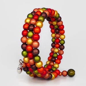 May include: A multi-strand wrap bracelet featuring colorful beads in shades of red, orange, yellow, green, and brown. The bracelet has a silver-toned heart charm and is designed to wrap around the wrist multiple times.