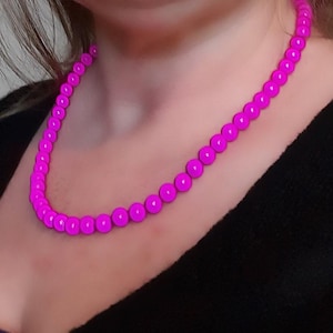 Op de afbeelding: Een felroze kralenketting met ronde kralen.