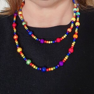 May include: A layered rainbow beaded necklace with round, colorful beads. The necklace is made of wood and has a glossy finish.