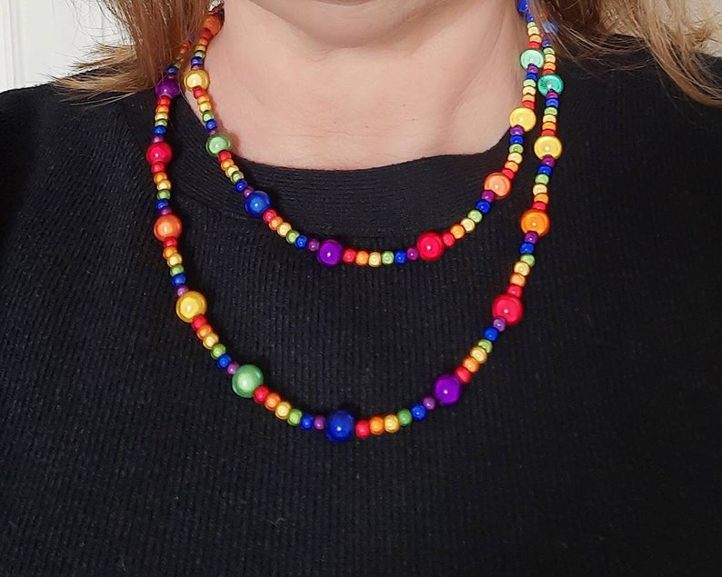 May include: A layered rainbow beaded necklace with round, colorful beads. The necklace is made of wood and has a glossy finish.