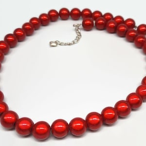 May include: A red beaded necklace with a silver chain clasp. The beads are round and have a shiny finish.