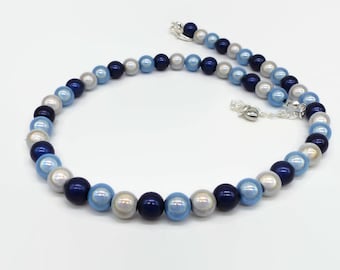 May include: A necklace with a mix of blue, light blue, and silver beads. The necklace has a silver clasp and chain. The beads are round and evenly spaced, creating a classic and elegant look.