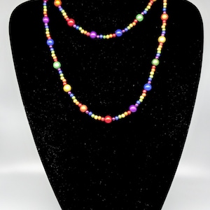 May include: A long rainbow beaded necklace with alternating colors of red, orange, yellow, green, blue, indigo, and violet.