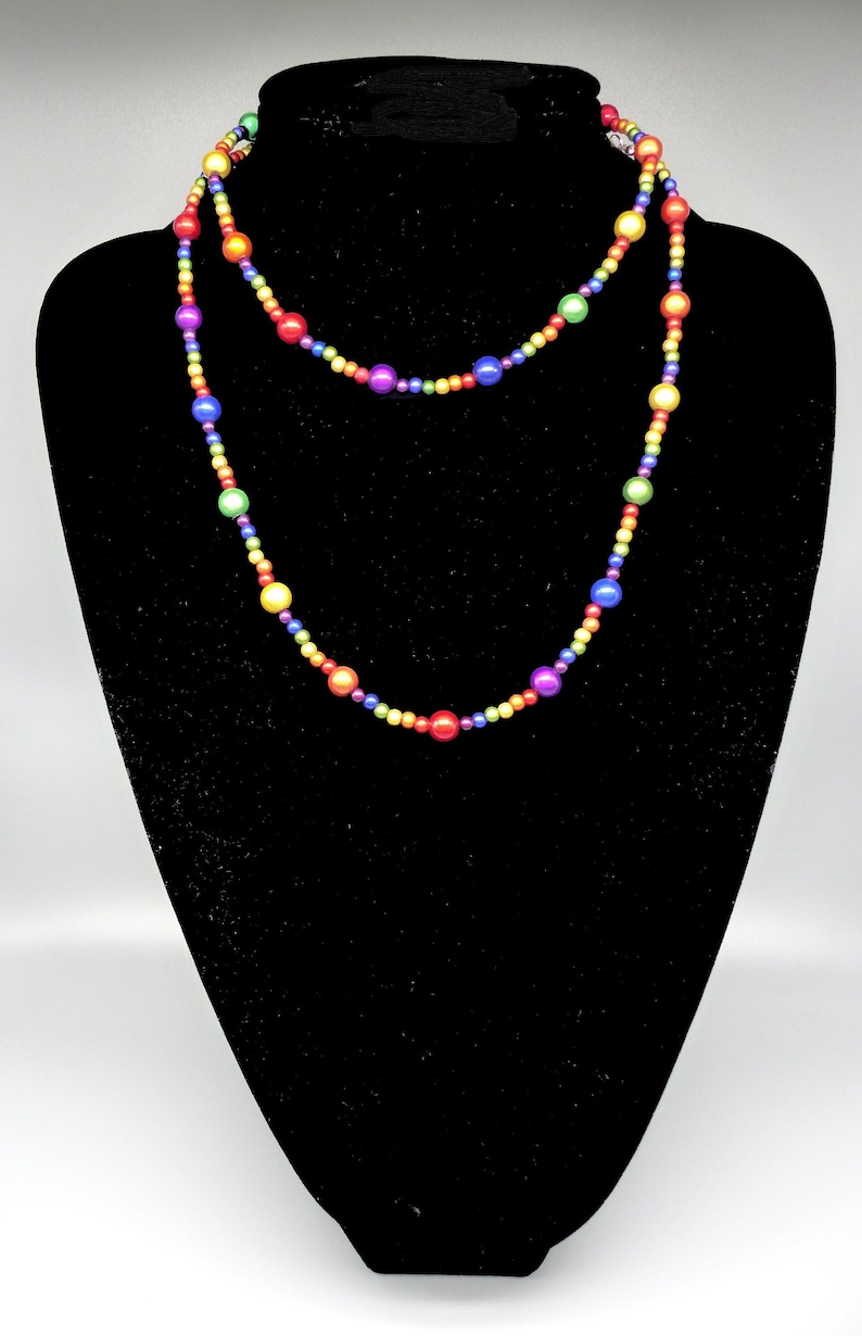 May include: A long rainbow beaded necklace with alternating colors of red, orange, yellow, green, blue, indigo, and violet.