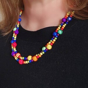 May include: A multi-colored beaded necklace with round beads in shades of red, orange, yellow, green, blue, and purple.