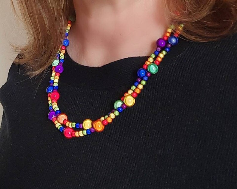 May include: A multi-colored beaded necklace with round beads in shades of red, orange, yellow, green, blue, and purple.