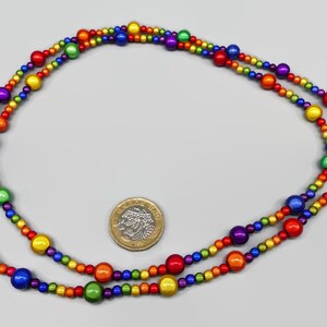 May include: A rainbow beaded necklace with a silver clasp. The beads are arranged in a rainbow pattern, with red, orange, yellow, green, blue, indigo, and violet beads.