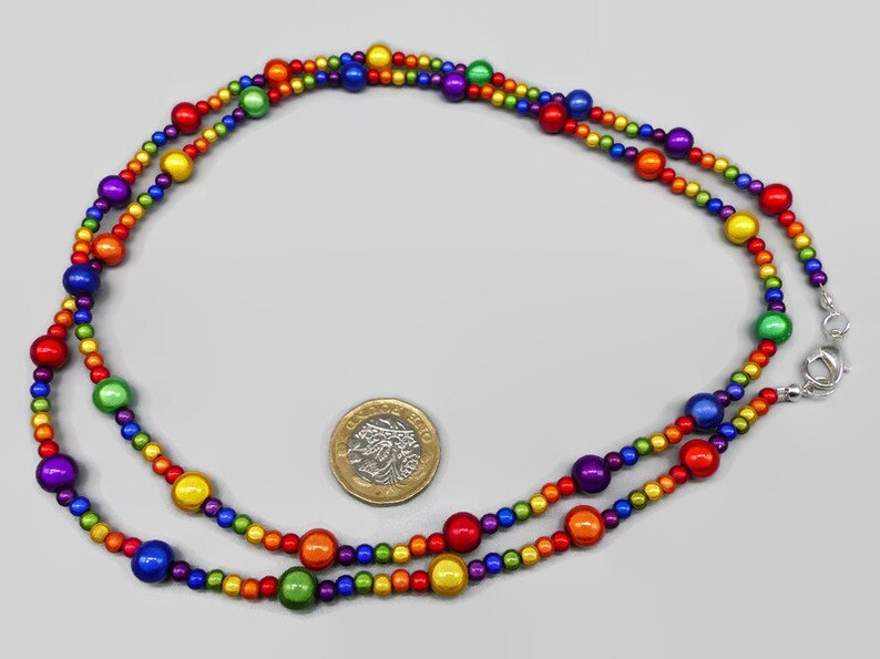 May include: A rainbow beaded necklace with a silver clasp. The beads are arranged in a rainbow pattern, with red, orange, yellow, green, blue, indigo, and violet beads.