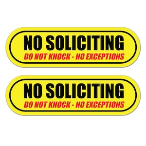 May include: Two yellow oval signs with black text that reads "NO SOLICITING" above "DO NOT KNOCK - NO EXCEPTIONS" in red. The signs have a black border.
