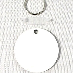 May include: A white blank round metal keychain tag with a hole in the center. The tag is accompanied by a silver key ring and a clear plastic protective sheet.