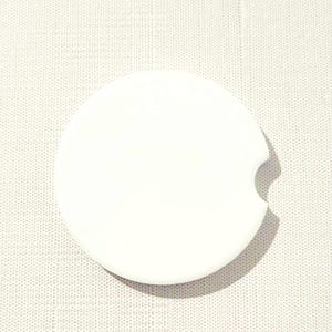May include: White round coaster with a cut-out for a beverage. The coaster is made of a smooth, durable material.