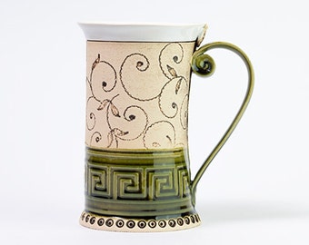 May include: A ceramic mug with a green and white design. The mug has a white rim and a green handle. The design features a repeating pattern of swirls and leaves.