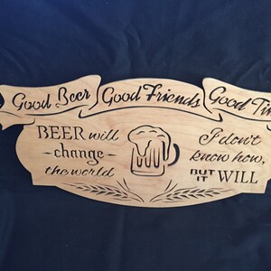 May include: Wooden sign with the words "Good Beer, Good Friends, Good Times" and the phrase "Beer will change the world." Features a beer mug graphic. The sign is made of light-colored wood.