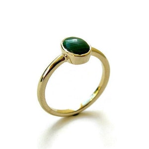 Puede incluir: Un anillo de oro con una piedra preciosa ovalada verde.