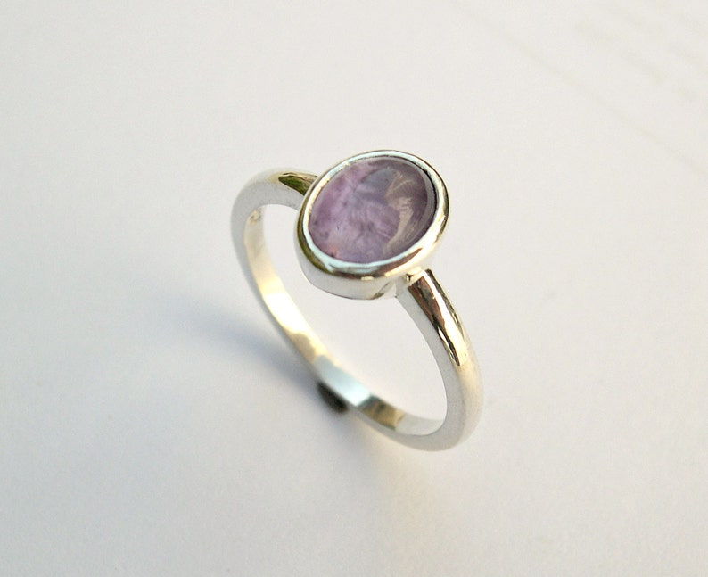 May include: A silver ring with a light purple oval gemstone.