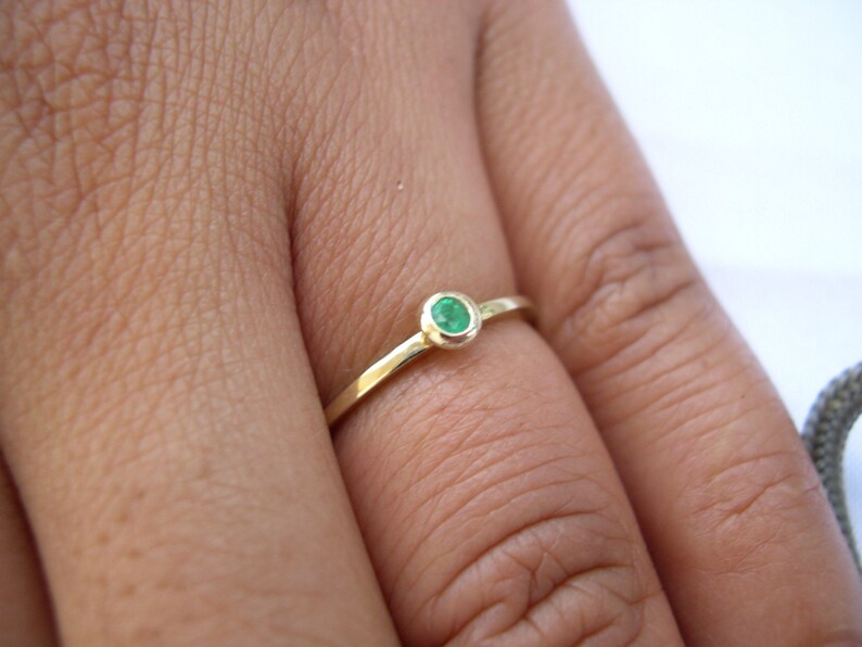 May include: A simple gold ring with a small, round, green gemstone.
