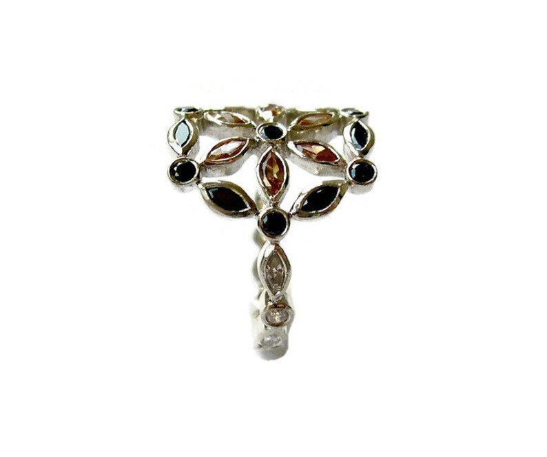 Puede incluir: Un anillo de plata con un dise&ntilde;o floral con piedras preciosas negras, marrones y transparentes.