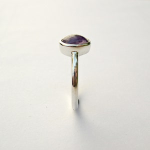 May include: A silver ring with a purple gemstone set in a bezel setting.