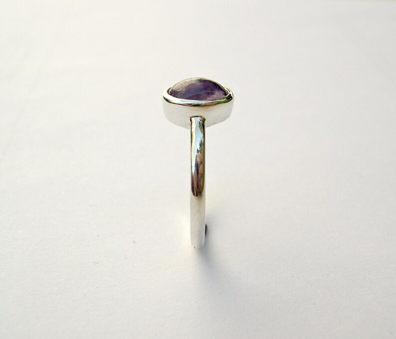 May include: A silver ring with a purple gemstone set in a bezel setting.