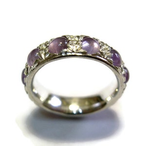 May include: A silver band ring with a row of purple gemstones and smaller clear gemstones.