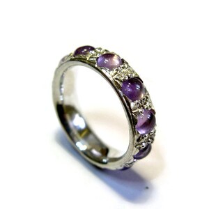 May include: A silver band ring with a row of purple gemstones set in the band.