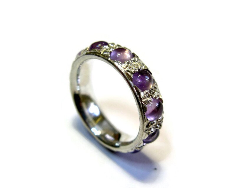 May include: A silver band ring with a row of purple gemstones set in the band.