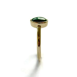 Puede incluir: Un anillo de oro con una piedra ovalada verde.