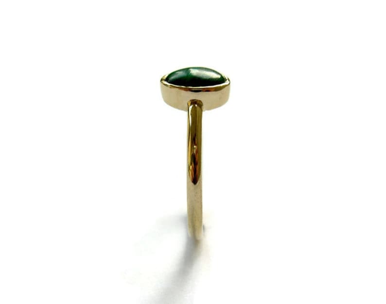 Puede incluir: Un anillo de oro con una piedra ovalada verde.