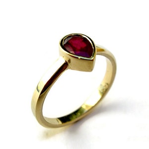 Op de afbeelding: Een gouden ring met een peervormige robijn.