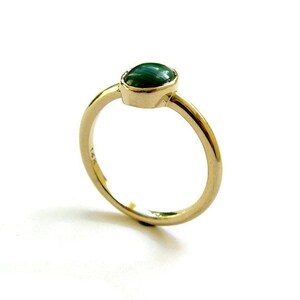 Puede incluir: Un anillo de oro con una piedra ovalada verde.