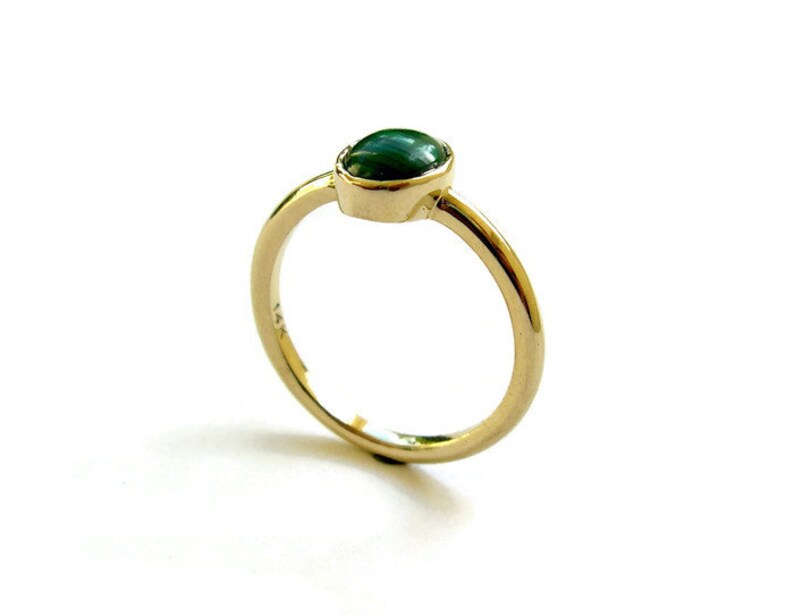 Puede incluir: Un anillo de oro con una piedra ovalada verde.