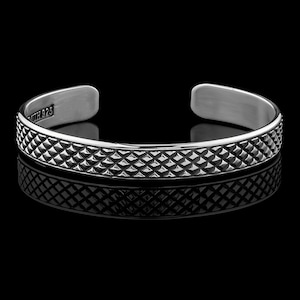 Könnte beinhalten: Ein silbernes Armband mit einem strukturierten Diamantenmuster. Das Armband ist offen und hat einen Verschluss an der Seite. Das Armband ist innen mit "925" gekennzeichnet.