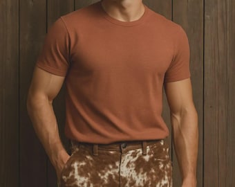 May include: A rust-colored, short-sleeved t-shirt paired with brown and white patterned shorts. The shorts have a cowhide-like design. The outfit is casual and suitable for warm weather.