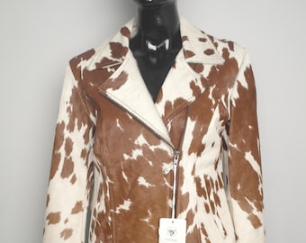 May include: A brown and white cowhide leather jacket with a zip closure, displayed on a mannequin. The jacket has a classic collar and a brown and white pattern. A tan baseball cap with decorative stitching is on the mannequin's head.