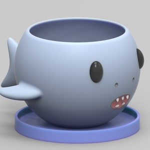 May include: A light blue ceramic planter shaped like a shark with black eyes and a pink mouth. The planter has a separate light blue saucer.
