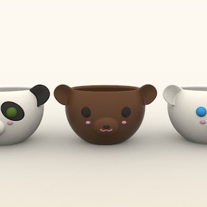 May include: Three ceramic cups with animal faces. The cups are white, brown, and white with black markings. The white cups have blue eyes and the brown cup has black eyes. All cups have pink noses and mouths.