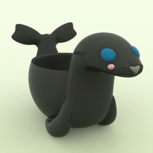 May include: A black ceramic seal planter with a bow-shaped tail and blue eyes. The planter has a small opening on the top for planting.