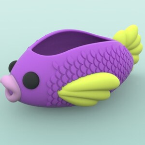 May include: Purple fish-shaped container with yellow fins and a black eye. The container has a textured surface that resembles scales.