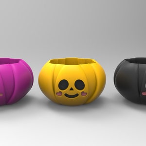 Pode incluir: Três recipientes de doces em forma de abóbora de Halloween. Os recipientes são rosa, amarelo e preto. Cada recipiente tem um rosto sorridente com olhos, nariz e boca. Os recipientes são perfeitos para guardar doces ou outras guloseimas pequenas.