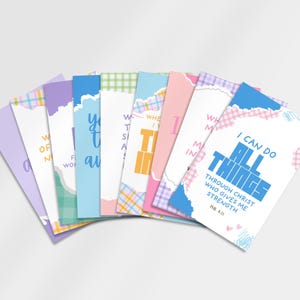 May include: A set of rectangular cards arranged in a fan shape, featuring pastel-coloured borders with plaid and torn paper patterns. The cards display various inspirational phrases in blue, orange, and pink text, including I CAN DO ALL THINGS.