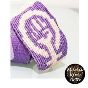 Puede incluir: Pulsera de amistad de color morado y blanco con un diseño de mano blanca. La pulsera está hecha con una técnica de anudado.