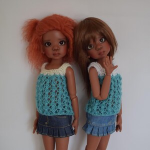 Puede incluir: Dos muñecas de piel morena con tops de crochet azul y blanco y faldas de mezclilla. La muñeca de la izquierda tiene el pelo rojo y la muñeca de la derecha tiene el pelo marrón.