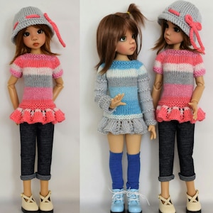 Puede incluir: Dos muñecas con suéteres de punto a rayas y sombreros. Una muñeca lleva un suéter a rayas rosa y blanco con un sombrero gris y un lazo rosa. La otra muñeca lleva un suéter a rayas azul y blanco con un sombrero gris y un lazo blanco. Ambas muñecas llevan pantalones vaqueros y zapatos.