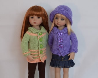 May include: Two dolls wearing knitted cardigans. The doll on the left is wearing a green and peach cardigan with brown leggings and green sneakers. The doll on the right is wearing a purple cardigan with a blue denim skirt and blue sneakers.