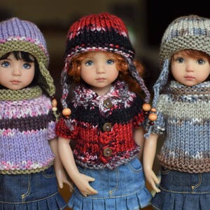 May include: Three knitted dolls wearing colorful hats and sweaters. The dolls have long brown hair and blue eyes. The dolls are wearing denim skirts.