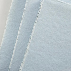 Puede incluir: Pila de papel hecho a mano de color azul claro con bordes irregulares.